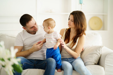 family time, weekend, leisure activities, parenting. mother, father and little son in living room. daddy and mom playing with baby boy