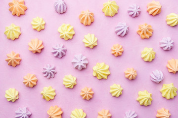 Fototapeta na wymiar creative pattern of colorful meringues on pastel pink background. minimal food concept. dessert design mockup, confectionery