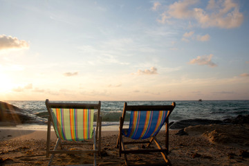 Summer vacation deckchairs on tropical beach and ocean sea at sunrise background. Travel and vacation holiday.