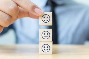 Hand of a businessman chooses a smiley face on wood block cube, The best excellent business...