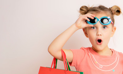 beautiful girl wearing dress and sunglasses holding shopping bags