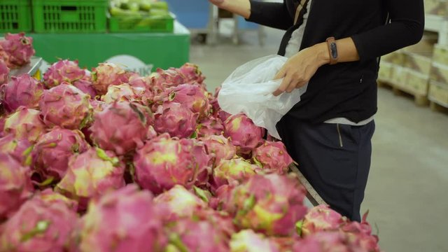 image of a woman standing alone chooses dragon fruit when in a supermarket