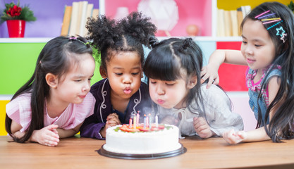 Group diversity kids blowing birth day cake.