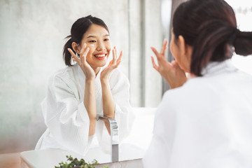 Asian woman cleaning face front of mirror, skin care and cosmetic removal concept