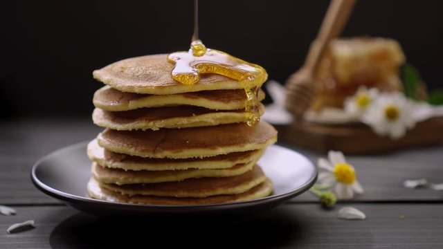 Honey dripping on the stack of pancakes for breakfast on the wooden table, healthy products by organic natural ingredients concept