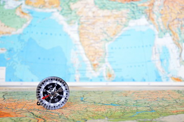 magnetic compass on a blurred background of earth geography map 