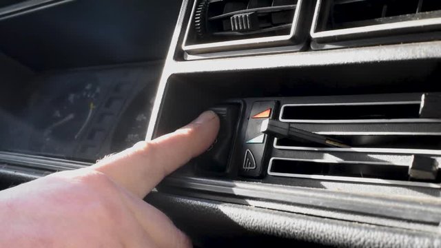 The person in the retro car turns the buttons on and off, moves the sliders and toggle switch, checking the flow of cold and hot air to heat the car interior and passengers . Close-up shot