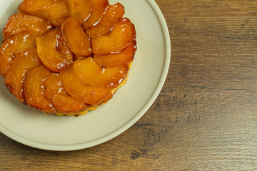 Freshly baked homemade Apple Tarte Tatin on a gray plate on a wood table top.	