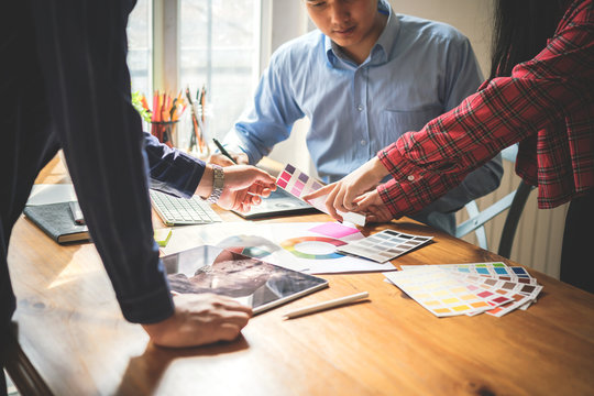 Young woman designer giving some new ideas about new business project to her partners in workplace. Group of young designers brainstorming concept