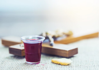 Close-up of a wine glasses  and  bread  with blurred of crucifix on  table with window light, christian background with copy space