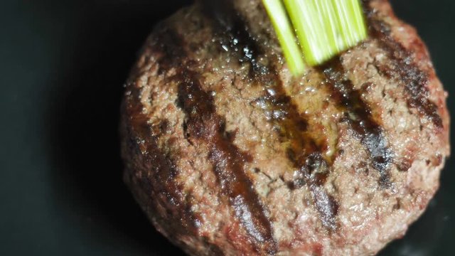 The finished meat patty with a grill imprint is smeared with vegetable olea