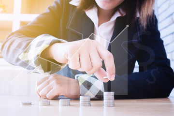 Woman with black suit putting coins on stack with holding money, Concept business, finance, money saving and investment,on office background