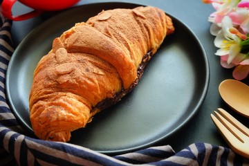 Close up of croissant on black plate.