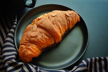 Close up of croissant on black plate.