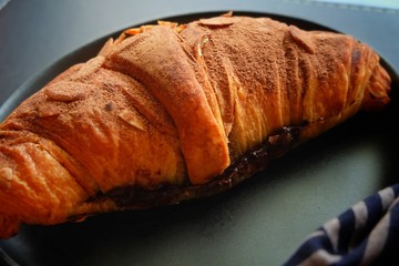 Close up of croissant on black plate.