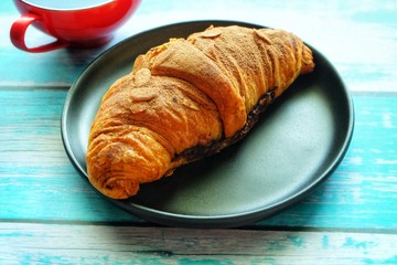 Close up of croissant on black plate.