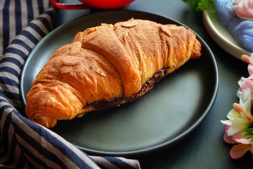 Close up of croissant on black plate.