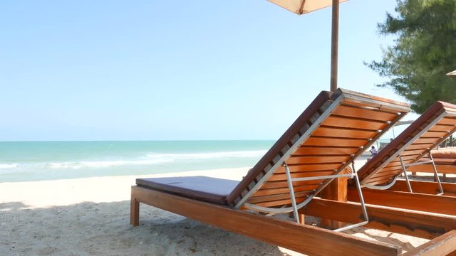 Relaxing beach chair on the sandy beach with a canopy. A view of sea waves hitting the shore. A shade to relax on the beach, vacation concept.