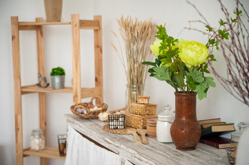 Summer kitchen interior in rustic style. Bright kitchen with a wooden table. Spring flowers and bread in a basket on the table in the kitchen