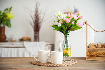 Summer kitchen interior in rustic style. Bright kitchen with a wooden table. Spring flowers and bread in a basket on the table in the kitchen