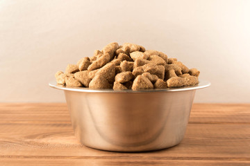 Bowl with dog food on a wooden table. Close up.