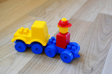 Toy car made of colorful plastic blocks on wooden texture floor background. Concept of educational and developing toys for children.