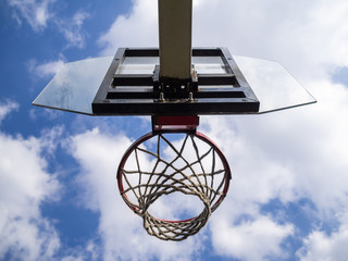 Basketball ring against the background of the blue sky with clouds. Sports ground