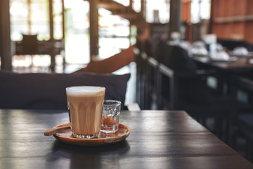 Closeup image of a glass of hot coffee on wooden table in cafe