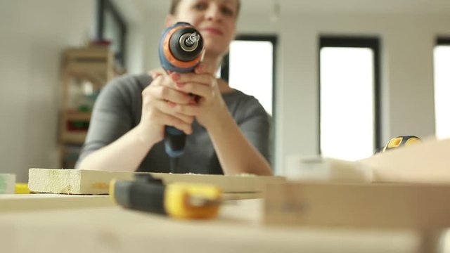 Woman aiming a drill at the camera. Drill in the hand of a young woman.  