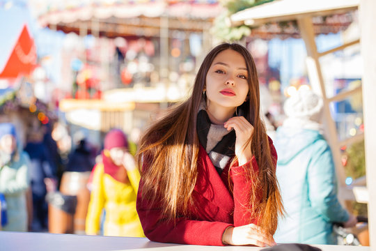 Young beautiful brunette woman in red coat posing on winter park