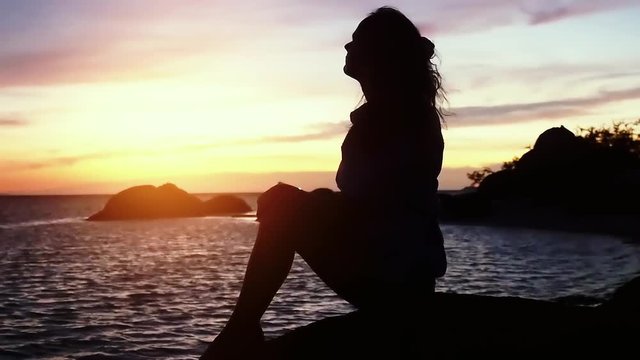 Pensive dreaming woman on beach looking at the sea during beautiful sunset. Slow Motion. 1920x1080