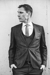 A man in a checkered suit poses on the street to advertise men's clothing. Black and white photo. Advertising menswear