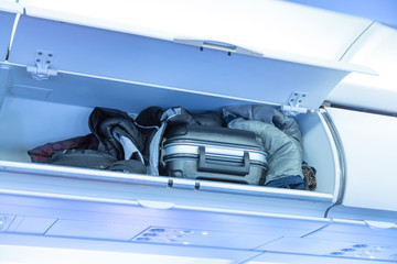 Luggage shelf with baggage suitcase in an airplane. Aircraft interior. Travel concept.