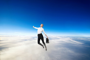 Businesswoman in formal wear flying in blue sky.
