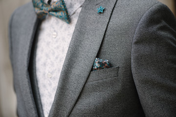 A man with a beard and sunglasses in a gray suit poses on the street to advertise men's clothing. Advertising menswear