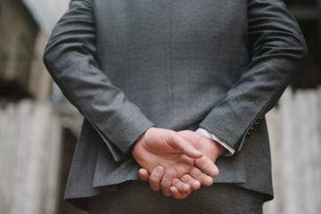 A man with a beard and sunglasses in a gray suit poses on the street to advertise men's clothing. Advertising menswear