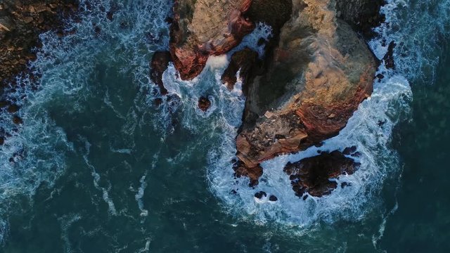 Aerial top view on Atlantic coast with rock cliffs and waves at sunset in Portugal, 4k