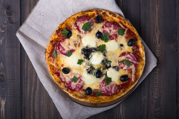 Pizza served with dill. Pizza with tomatoes black olives and ham.