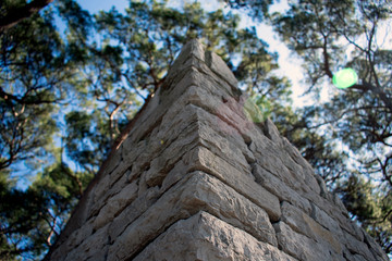 Close up of a stone wall corner, with trees an sky in background