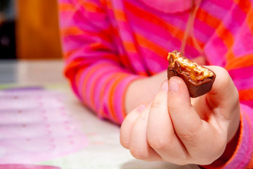 Little girl eating Snickers chocolate bar for breakfast