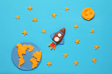 Creative craft plasticine rocket in open space, astronaut dreams. Stars, planet earth and moon....