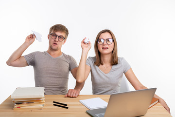 Playful, naughty students with big glasses throwing paper airplanes and crumpled paper sitting at...