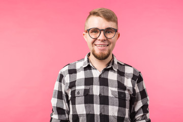 Portrait of a smiling bearded man in eyeglasses looking at camera isolated over pink background