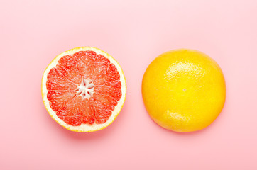 Halved grapefruit on a pink background. Refreshing summer tropical fruit. Minimal composition. Top view, flat lay.