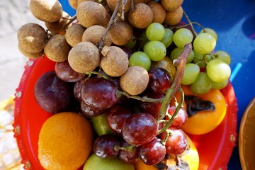 Naklejka na ściany i meble Top view of mixed fruit are fresh ripe red and green grape, longan, guava and persimmon in red plate, healthy food concept