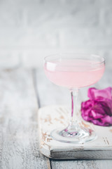 Summer refreshment drinks. Light pink rose cocktail, with rose wine on a white table. With rose flowers. Copy space