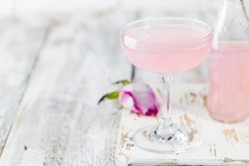 Summer refreshment drinks. Light pink rose cocktail, with rose wine on a white table. With rose flowers. Copy space