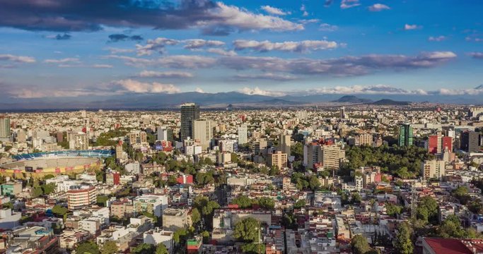 Aerial hyperlapse o a very clear afternoon in Mexico City with the Azul stadium, the Bullring of Mexico, some skycrapers, the Hundido park and the volcanoes with snow at the back.
