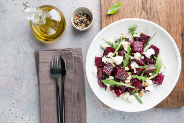 beetroot salad with blue cheese, arugula and walnut in a white plate on gray background, top view