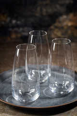 Empty transparent glasses on tray over stone background